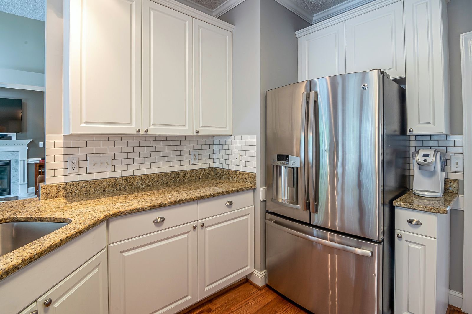 Bright kitchen with stainless steel refrigerator and granite counters